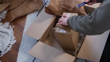 Kırtasiye bıçağıyla eli olan bir adam posta kutusunu açıp yakın plan kesiyor. Adam paketleri boşaltıyor. Genç adam e-ticaret ya da çevrimiçi market kutusunu açıyor. Yüksek kalite 4k görüntü