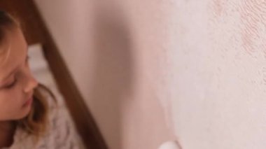 Bir kız rulo ile duvarı beyaza boyuyor ve dans ediyor. Yüksek kalite 4k görüntü