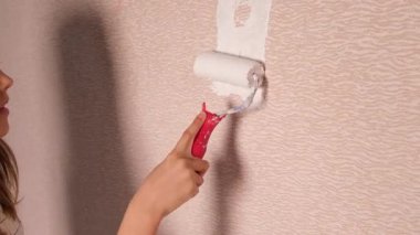 Bir kız rulo ile duvarı beyaza boyuyor ve dans ediyor. Yüksek kalite 4k görüntü