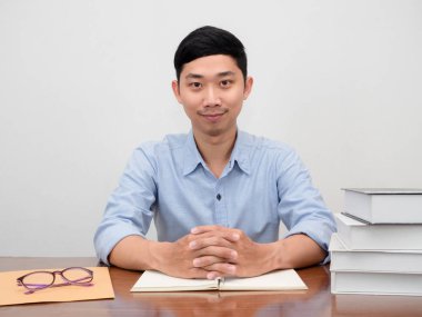 Yakışıklı iş adamı çalışma masasında kendine güvenen bir gülümseme ile oturuyor.