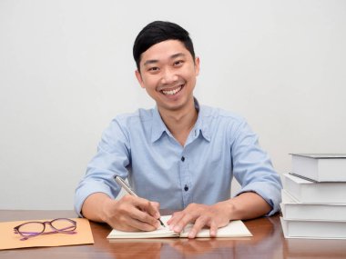 Pozitif Asyalı iş adamı çalışma masasında oturur kameraya gülümser.