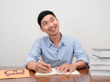 Pozitif Asyalı iş adamı iş yerinde oturur ve gülümser.