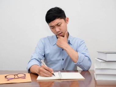 Asyalı işadamı çalışma masasında otururken çalışma konusunda ciddi ve düşünceli hissediyor.