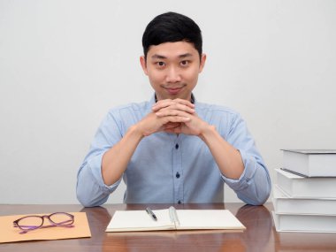 Pozitif Asyalı iş adamı çalışma masasına oturur mutlu bir şekilde gülümser ve kendine güvenir.