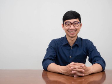 Yakışıklı Asyalı iş adamı gözlük takıyor. Masaya oturup gülümsüyor ve sana bakıyor.