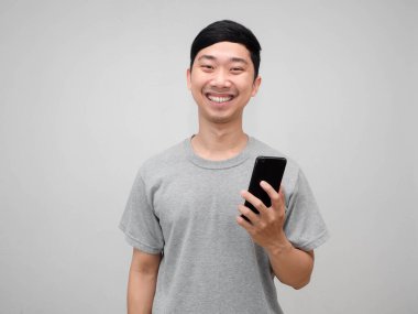 Pozitif yakışıklı adam gri gömlekli, cep telefonlu, mutlu gülümsemeli, izole edilmiş.