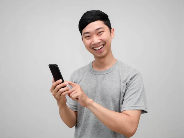 陽気アジア人男性グレーシャツを保持携帯電話幸せな笑顔隔離 — ストック写真