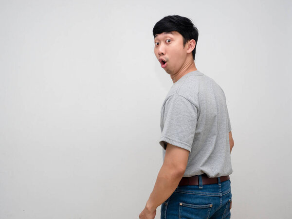 Asian young man grey shirt feels amazed turn back to looking isolated