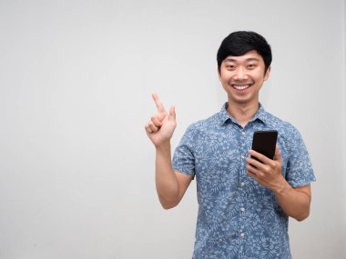 Neşeli Asyalı adam gülümsüyor. Elinde cep telefonu işaret parmağı var.