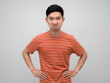 Asian man striped shirt stand hand at waist feels angry looking at you isolated