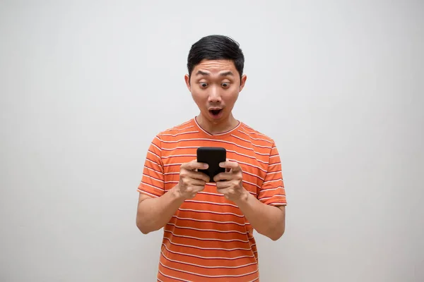 Man Oranje Shirt Voelt Verbaasd Kijken Naar Mobiele Telefoon Zijn — Stockfoto