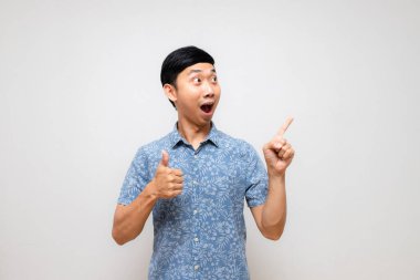 Pozitif Asyalı erkek mavi gömleği hayretler içinde baş parmağını göstererek kendini izole etti.