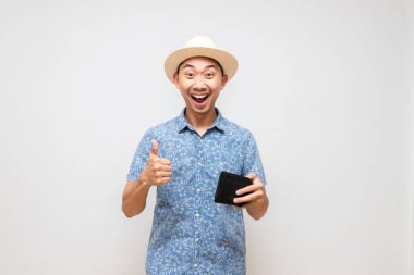 Pozitif Asyalı erkek mavi gömlek, şapka takıyor, cüzdan taşıyor.