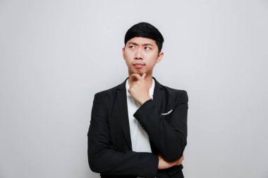 Asyalı siyah takım elbiseli, çapraz kollu düşünceli ve düşünceli.