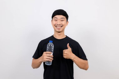 Pozitif Asyalı erkek siyah tişört mutlu gülüş su şişesini tut ve parmağını izole edilmiş olarak göster.