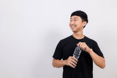 Pozitif Asyalı erkek siyah gömlek jesti açık su şişesi mutlu bir gülümseme ile izole yere bak