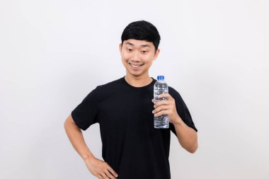 Pozitif Asyalı erkek siyah gömlek jesti mutlu bir gülümsemeyle açık su şişesi izole yere bak