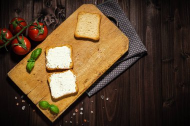 Krem peynir ve dilimlenmiş ekmeğin kahvaltı fotoğrafı. Ahşap arkaplanda domates.