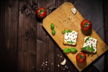 Krem peynir ve dilimlenmiş ekmeğin kahvaltı fotoğrafı. Ahşap arkaplanda domates.