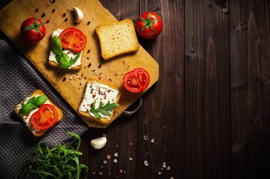 Krem peynirli lezzetli ekmek, ahşap masada domates ve bazilika, düz yatak. Metin için boşluk