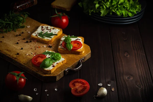 クリームチーズと自家製サンドイッチ コピースペースと暗い木製の背景にライ麦パンのクリスピースライス上のサラダとトマト — ストック写真