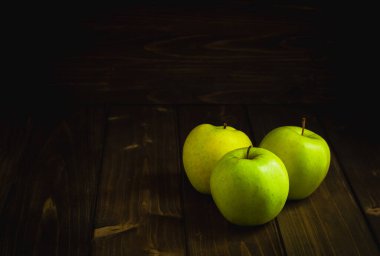 Olgun yeşil elma, siyah meşe arka planda, ahşap bir masada.