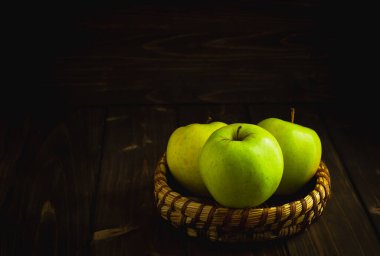 Tahtadaki kasede yeşil organik sağlıklı elmalar. Sağlıklı besinler karanlık arka plan