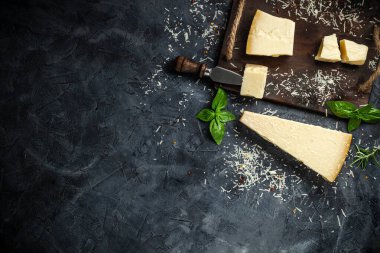 Siyah taşlı arka planda peynir bıçaklı sert peynirler. Parmesan peyniri. Üst Manzara. Metnin için boş yer.