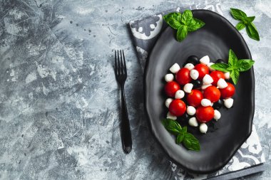 Kiraz domatesli Caprese, mini mozzarella, taze fesleğen yaprağı, geleneksel İtalyan yemeği, antipasto. afiş, menü, metin için tarif yeri, üst görünüm