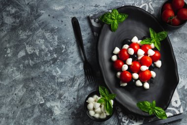 Kiraz domatesli Caprese, mini mozzarella, taze fesleğen yaprağı, geleneksel İtalyan yemeği, antipasto. afiş, menü, metin için tarif yeri, üst görünüm