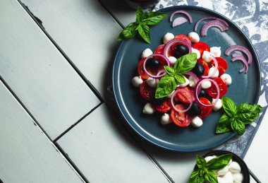 Caprese - geleneksel İtalyan sebze salatası, beyaz ahşap bir masada mozzarella peyniri ile. Kopyalama alanı olan üst görünüm.