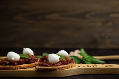 Kuru domates, mozzarella ve ahşap arka planda fesleğen. Boşluğu kopyala