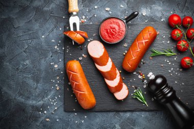 Siyah taşlı servis panosunda ızgara domuz sosisi, koyu bir arka planda izole edilmiş. Üst görünüm