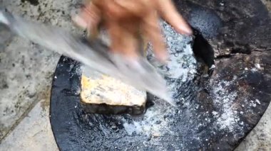 Yaşlı bir adam bir bıçağı bilemek için ıslak taş kullanıyor. Geleneksel Tayland usulü keskin bir bıçak yapmak onu bilenen bir taşa ileri geri sürmeyi gerektirir. Bıçağı el yağmuruna tut..
