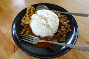 Tavuklu köri (Panang Kai) tarifi ve ahşap masada yasemin pilavı. Fıstıklı, hindistancevizli ve etli Tayland mutfağı. Tayland tarzı fast food.