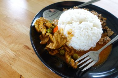 Tavuklu köri (Panang Kai) tarifi ve ahşap masada yasemin pilavı. Fıstıklı, hindistancevizli ve etli Tayland mutfağı. Tayland tarzı fast food.