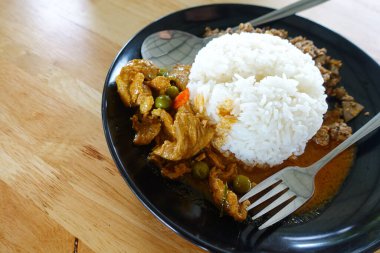 Tavuklu köri (Panang Kai) tarifi ve ahşap masada yasemin pilavı. Fıstıklı, hindistancevizli ve etli Tayland mutfağı. Tayland tarzı fast food.