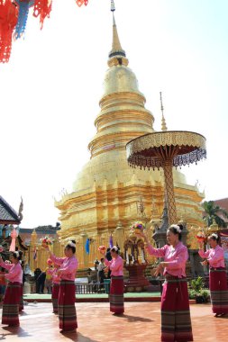 LAMPHUN -THAILAND: November 11, 2023:  Beautiful senior women perform an ancient Thai dance showing dancing in buddhist religious ceremony in TWat Phra That Haripunchai Woramahawihan. Thai nail dance with flower.
