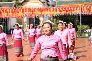 LAMPHUN -THAILAND: November 11, 2023:  Beautiful senior women perform an ancient Thai dance showing dancing in buddhist religious ceremony in TWat Phra That Haripunchai Woramahawihan. Thai nail dance with flower.