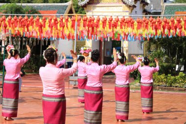 LAMPHUN -THAILAND: November 11, 2023:  Beautiful senior women perform an ancient Thai dance showing dancing in buddhist religious ceremony in TWat Phra That Haripunchai Woramahawihan. Thai nail dance with flower.