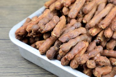 Kabuksuz tropik tamarind meyvesi, görünür tohumlar ve iç hamurla, bir ağaçtaki galvanize bir tepside. Tayland usulü gıda koruma kavramı. Soyulmuş demirhindi yemeye hazır bir kavramdır..