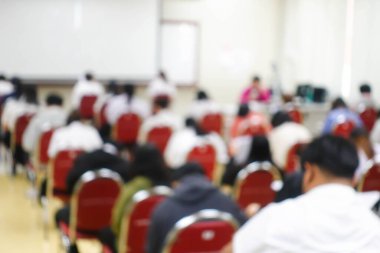 Sınav odasının arka planı bulanık ve içinde üniversite öğrencileri var. Muayene odasında son testi yapan bir öğrencinin bulanık görüntüsü. Üniversitedeki çalışma koltuklarının bulanık görünümü.