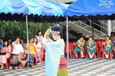 Lampang, Tayland - 7 Kasım 2024: Geleneksel Tayland kıyafetleri içinde bir grup Asyalı kadın ve erkek Ngao Köprüsü 'nde Tanrı' ya Çiçek Veren Sarı Çiçekler Festivali 'nde dans ediyor.