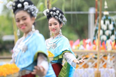 Lampang, Tayland - 7 Kasım 2024: Geleneksel Tayland kıyafetleri içinde bir grup Asyalı kadın ve erkek Ngao Köprüsü 'nde Tanrı' ya Çiçek Veren Sarı Çiçekler Festivali 'nde dans ediyor.