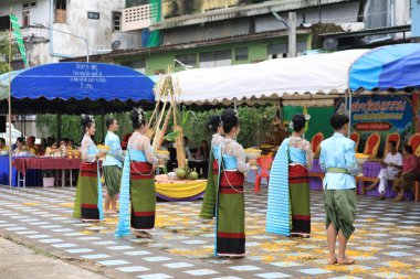 Lampang, Tayland - 7 Kasım 2024: Geleneksel Tayland kıyafetleri içinde bir grup Asyalı kadın ve erkek Ngao Köprüsü 'nde Tanrı' ya Çiçek Veren Sarı Çiçekler Festivali 'nde dans ediyor.