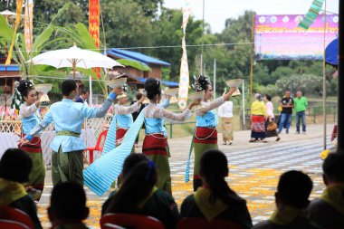 Lampang, Tayland - 7 Kasım 2024: Geleneksel Tayland kıyafetleri içinde bir grup Asyalı kadın ve erkek Ngao Köprüsü 'nde Tanrı' ya Çiçek Veren Sarı Çiçekler Festivali 'nde dans ediyor.