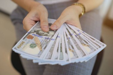 Para elinde, el ele tutuşan dolar banknotları. 