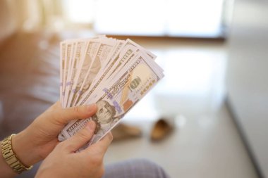 Para elinde, el ele tutuşan dolar banknotları. 