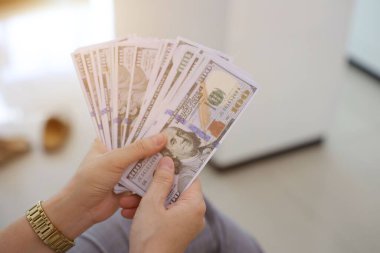 Para elinde, el ele tutuşan dolar banknotları. 