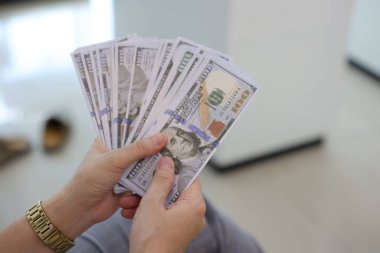 Para elinde, el ele tutuşan dolar banknotları. 